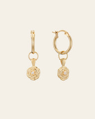 The Elsa Rose Pearl Earrings by CAMELLIA feature gold hoops with rose-shaped dangle charms, all set against an off-white background, handcrafted in New York.