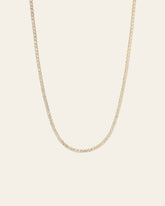 The Tennis Chain Necklace by CAMELLIA is a 14K yellow gold vermeil with small, evenly spaced diamonds, exuding elegance and hypoallergenic comfort against a plain backdrop.