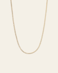The Tennis Chain Necklace by CAMELLIA is a 14K yellow gold vermeil with small, evenly spaced diamonds, exuding elegance and hypoallergenic comfort against a plain backdrop.