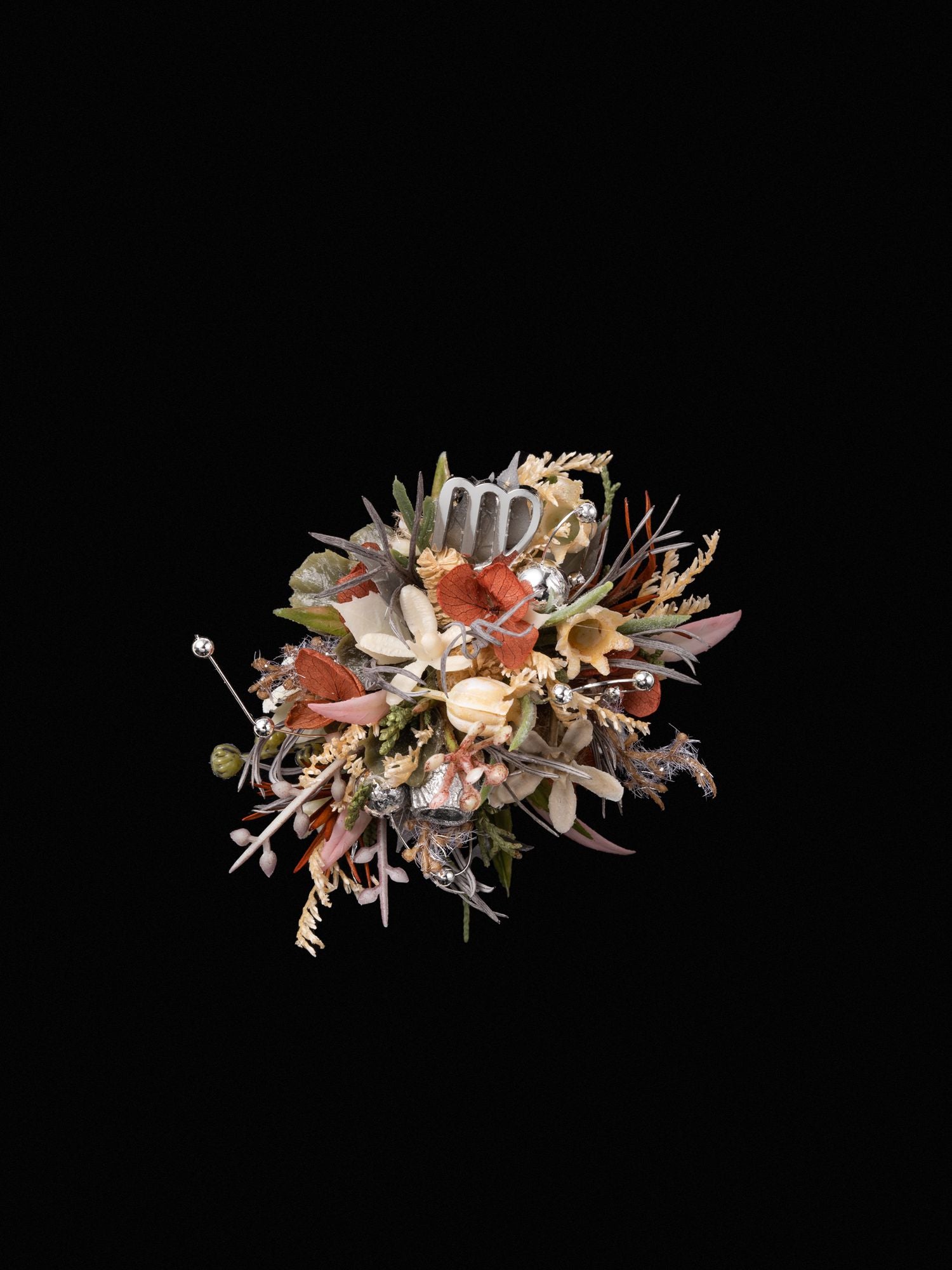 A decorative bouquet of dried flowers with assorted leaves and metallic elements on a black background elegantly mirrors the Virgo Flower Ring by CAMELLIA.