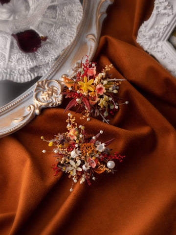 Burgundy floral arrangements with pearls sit on a soft brown fabric, accompanied by an ornate mirror and a glass fruit bowl. The wedding display is enhanced by the handcrafted CAMELLIA burgundy Theater Style Wedding Flower Rings, which feature an adjustable size for a custom fit. Burgundy floral arrangements with pearls sit on a soft brown fabric, accompanied by an ornate mirror and a glass fruit bowl. The wedding display is enhanced by the handcrafted CAMELLIA burgundy Theater Style Wedding Flower Rings, which feature an adjustable size for a custom fit.