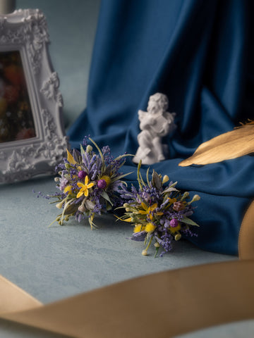 The Floral arrangement features yellow and purple flowers on a blue cloth, paired with a handcrafted white cherub statue, gold ribbon, and ornate frame. It mirrors the elegance of CAMELLIA's Dreamy Purple Green Wedding Flower Rings, showcasing unique beauty in every detail. The Floral arrangement features yellow and purple flowers on a blue cloth, paired with a handcrafted white cherub statue, gold ribbon, and ornate frame. It mirrors the elegance of CAMELLIA's Dreamy Purple Green Wedding Flower Rings, showcasing unique beauty in every detail.