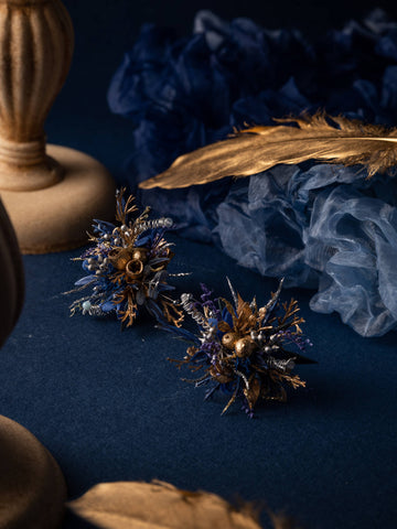 Blue and gold decorative floral arrangements from CAMELLIA, featuring preserved flowers, candles, and feathers elegantly set against a dark background. Find the Baroque Castle Wedding Flower Rings for your special event. Blue and gold decorative floral arrangements from CAMELLIA, featuring preserved flowers, candles, and feathers elegantly set against a dark background. Find the Baroque Castle Wedding Flower Rings for your special event.