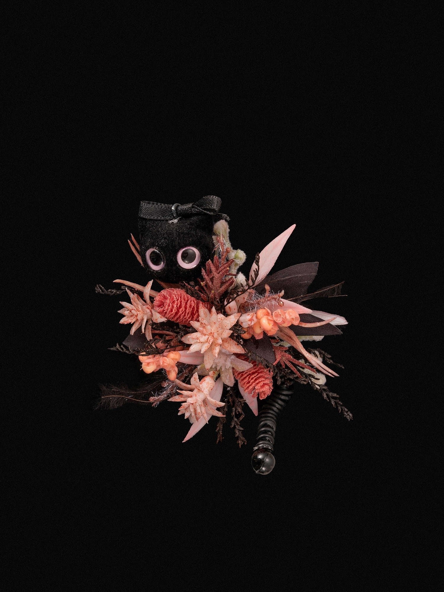 The CAMELLIA Cat Flower Ring features a handcrafted bouquet of pink and red flowers against a black background, accented by a fabric owl with large eyes and a black bowtie.