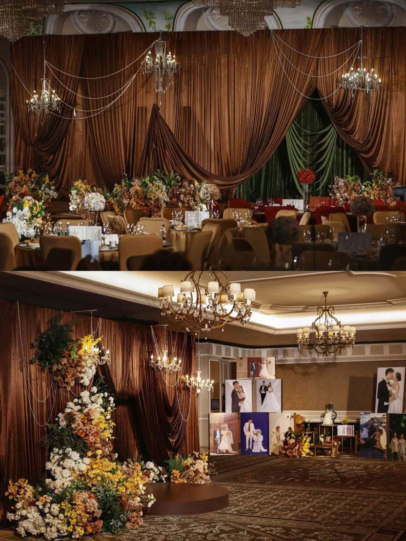 Elegant event venue with brown drapery and chandeliers features CAMELLIA's Medieval Gothic Wedding Flower Rings. Large framed photos adorn the walls, while tables are set with floral arrangements, glassware, and chairs.