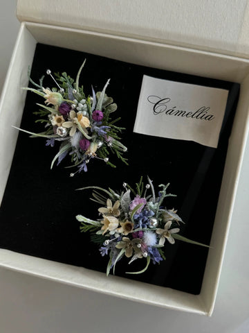 The Customized Unique Flower Ring by CAMELLIA is a lovingly handcrafted jewelry piece with purple, white, and green floral accents. It embodies elegance and charm, displayed in a black box with a card labeled "Camellia. The Customized Unique Flower Ring by CAMELLIA is a lovingly handcrafted jewelry piece with purple, white, and green floral accents. It embodies elegance and charm, displayed in a black box with a card labeled "Camellia.