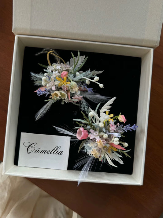 A white box containing two small, colorful floral arrangements and a card labeled