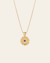 The Elsa Peony Sapphire Necklace by CAMELLIA features a sunflower-shaped pendant with a central blue gemstone, set in 14K yellow gold vermeil. Designed to be hypoallergenic, it's ideal for those with sensitive skin.