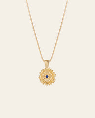 The Elsa Peony Sapphire Necklace by CAMELLIA features a sunflower-shaped pendant with a central blue gemstone, set in 14K yellow gold vermeil. Designed to be hypoallergenic, it's ideal for those with sensitive skin.