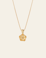 The CAMELLIA Elsa Poppy Peridot Necklace features a thin chain and a flower-shaped pendant with small gemstones at the center, crafted in hypoallergenic 14K yellow gold vermeil.
