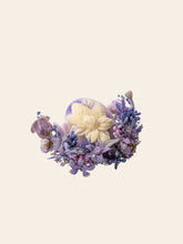 The Hyacinthus Birth Flower Ring by CAMELLIA is a handcrafted custom symbol flower ring from New York, showcasing a round object with floral patterns surrounded by purple and blue blossoms on a plain background.