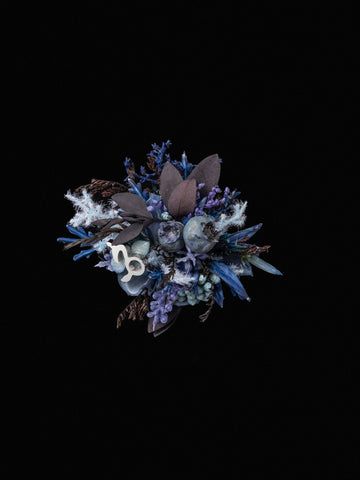 The Capricorn Flower Ring by CAMELLIA is a handcrafted small bouquet with dark purple, blue, and silver flowers on a black background, embodying the elegance of a custom ring. The Capricorn Flower Ring by CAMELLIA is a handcrafted small bouquet with dark purple, blue, and silver flowers on a black background, embodying the elegance of a custom ring.