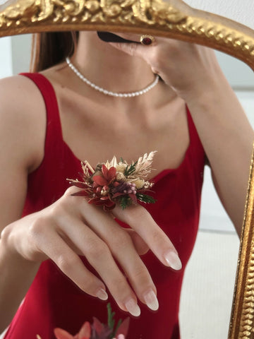 A person in a red dress, wearing a pearl necklace, takes a mirror selfie showcasing CAMELLIA's Customized Wedding Flower Ring on their left hand, featuring striking red and beige flowers. A person in a red dress, wearing a pearl necklace, takes a mirror selfie showcasing CAMELLIA's Customized Wedding Flower Ring on their left hand, featuring striking red and beige flowers.