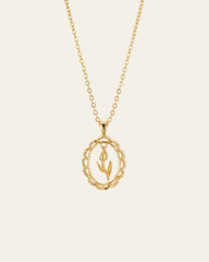 The CAMELLIA Tulip Flower Necklace is a 14K Yellow Gold Vermeil piece featuring a delicate chain and a pendant with a hand holding a tulip inside a textured circular frame.