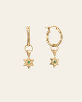 The CAMELLIA Elsa Lily Emerald Earrings feature two 14K Yellow Gold Vermeil hoop earrings with star-shaped pendants and green gemstones. Set against a light background, these hypoallergenic pieces blend style and comfort for sensitive ears.