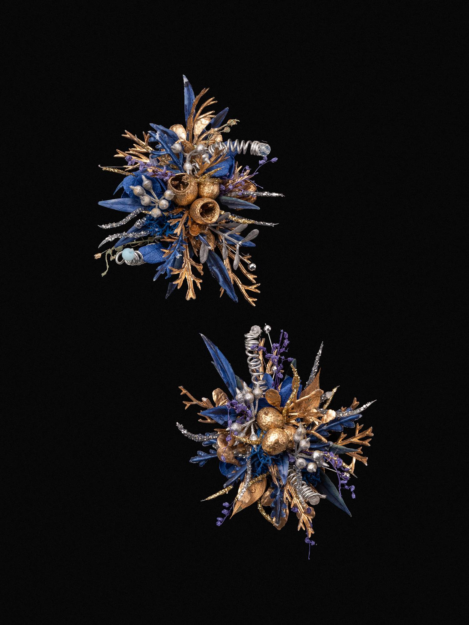 The Blue and Gold Baroque Castle Wedding Flower Rings by CAMELLIA display intricate floral arrangements with metallic textures and diverse plant shapes, set against a black background, embodying the elegance of preserved flowers.