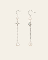 The Audrey Opal Pearl Earrings by CAMELLIA are elegant sterling silver pieces featuring dangling chains with a small pearl at the top, a star-shaped gem accent, and a larger pearl at the bottom.