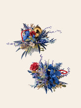 Two floral arrangements with blue, red flowers, green foliage, and gold accents are shown on a light background. Each resembles the handcrafted elegance of CAMELLIA's "Little Prince Wedding Flower Rings," echoing timeless charm crafted in New York.