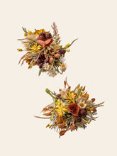 The Free Poetic Boho Wedding Flower Rings by CAMELLIA feature two autumn-themed arrangements with orange, yellow, and red artificial flowers and green and brown foliage, elegantly set against a neutral background.