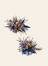 The CAMELLIA Blue and Gold Baroque Castle Wedding Flower Rings elegantly feature decorative arrangements of leaves, berries, and metallic elements on a light background, beautifully complementing the preserved flowers for an everlasting touch.