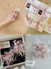 A hand holds a decorative jewelry box adorned with floral designs, perfect for handcrafted pieces. Nearby, similar ribbon-tied boxes are stacked. A close-up of a "CAMELLIA" box reveals intricate patterns inside, ideal for securing your favorite Customized Symbol Flower Ring.