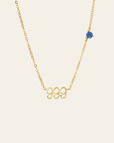 The CAMELLIA 999 Angel Number Choker is a sterling silver gold necklace accented with a small blue bead on the side, set against a plain background.