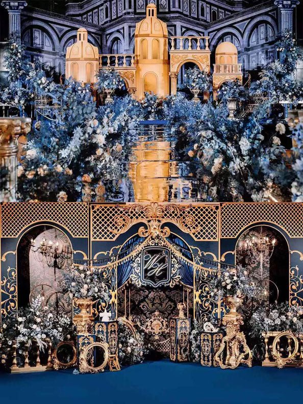 An opulent indoor scene boasts lavish gold and blue decor featuring CAMELLIA's Blue and Gold Baroque Castle Wedding Flower Rings, with intricate preserved floral arrangements and ornate architectural elements.