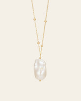 The Anastasia Pearl Necklace by CAMELLIA features a 14K yellow gold vermeil chain with small beads and a large baroque pearl pendant against a plain background.