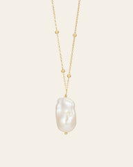 The Anastasia Pearl Necklace by CAMELLIA features a 14K yellow gold vermeil chain with small beads and a large baroque pearl pendant against a plain background.