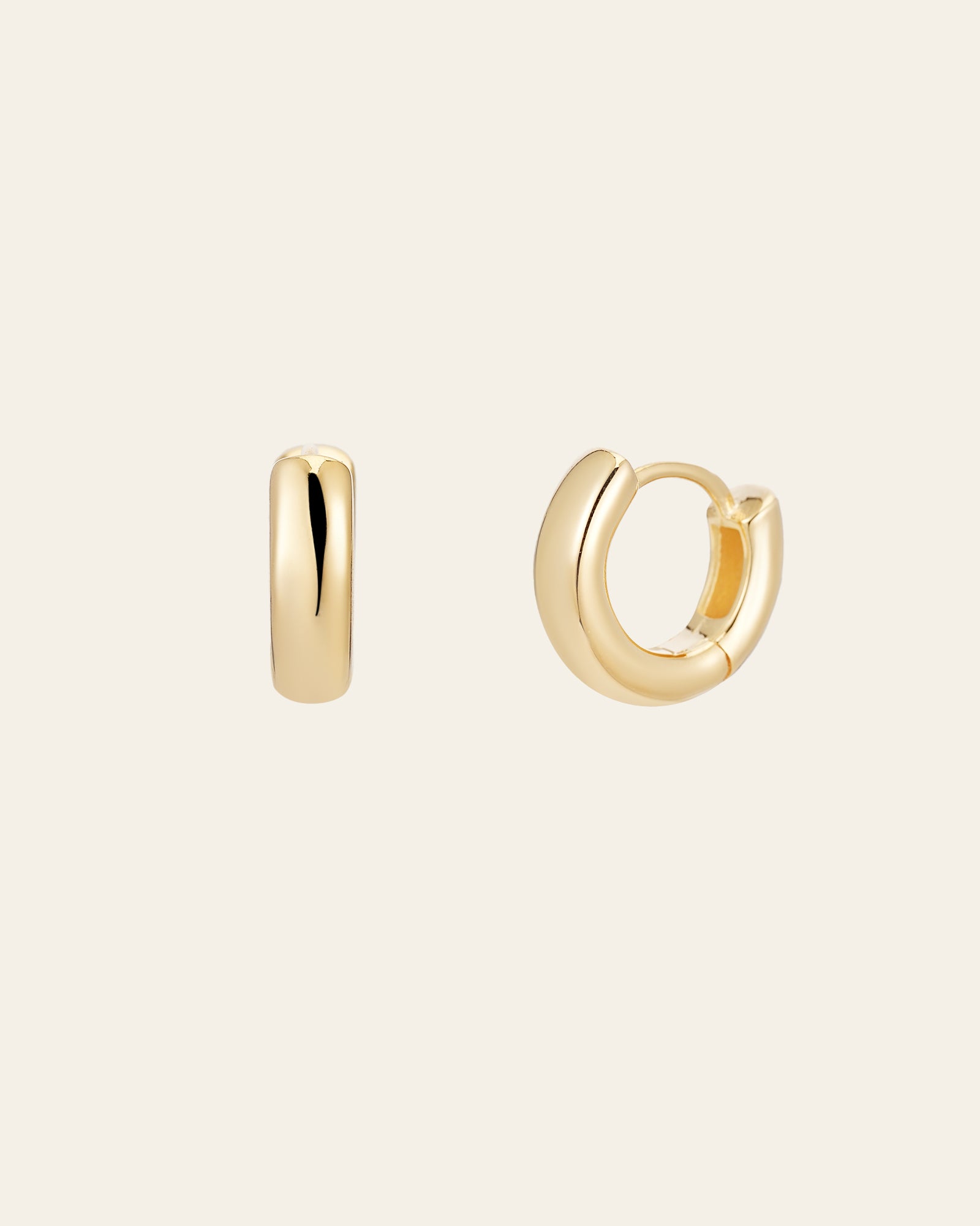 The Mia Hoops by CAMELLIA, two elegant small gold hoop earrings in 14K Yellow Gold Vermeil, are displayed on a plain background. One lies on its side while the other is partially open.