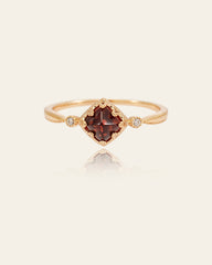 The CAMELLIA 14K Solid Gold Carena Garnet Ring features a vintage-inspired design with a square-cut deep red garnet center, accented by two small clear stones on each side.