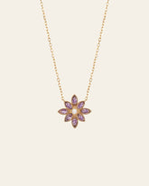 The Cámellia Amethyst Pearl Necklace by CAMELLIA features shimmering amethyst gemstones and a central yellow gem in a flower-shaped pendant crafted from 14K Yellow Gold Vermeil, set against a light background.
