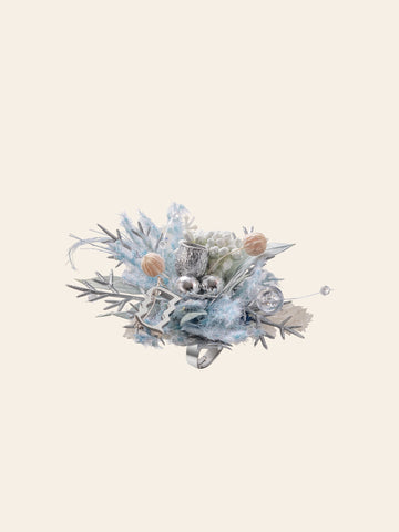 The Aquarius Flower Ring by CAMELLIA is a decorative arrangement of silver baubles, light blue foliage, and small pinecones, handcrafted in New York against a plain background. The Aquarius Flower Ring by CAMELLIA is a decorative arrangement of silver baubles, light blue foliage, and small pinecones, handcrafted in New York against a plain background.