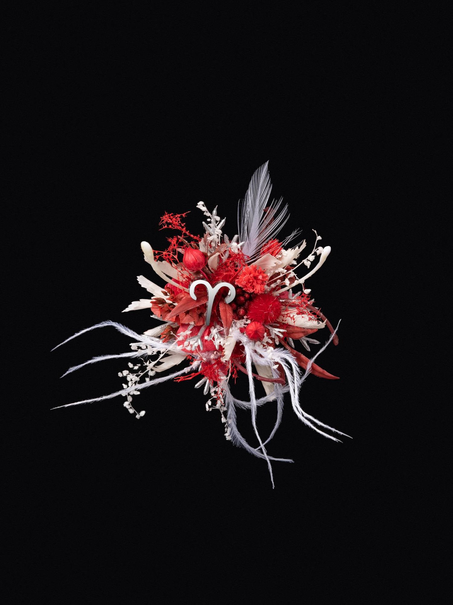The Aries Flower Ring by CAMELLIA showcases a vibrant, abstract floral arrangement with red, white, and pink elements handcrafted from feathers and curly ribbons on a black background. This customizable piece adds a unique touch to any setting.