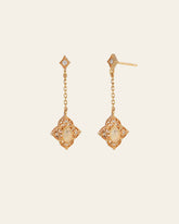 Aurielle Opal Dangle Earrings by CAMELLIA feature a gold, diamond-shaped design with intricate detailing and a central opalescent stone. These hypoallergenic earrings provide elegance and comfort for sensitive ears.