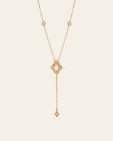 The Aurielle Opal Long Necklace by CAMELLIA is a hypoallergenic gold necklace featuring a central pearl pendant. It has a Y-shape design with diamond-shaped accents and small gems, ending in an elegantly long dangling chain.