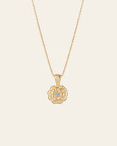 The Elsa Marigold Tourmaline Necklace by CAMELLIA features a gold flower-shaped pendant on a 14K Yellow Gold Vermeil chain with a central blue gemstone, set against a simple light background.