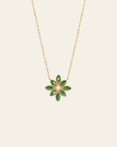 The Cámellia Emerald Pearl Necklace by CAMELLIA features a flower-shaped pendant with green marquise stones and a central pearl, set on a 14K yellow gold vermeil chain.