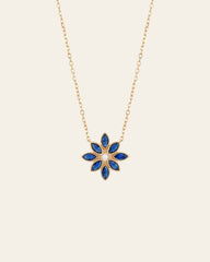 The Cámellia Sapphire Pearl Necklace by CAMELLIA showcases a blue and pearl flower-shaped pendant with seven petals, set against a plain white background.