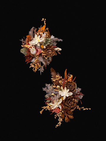The CAMELLIA Vintage Maillard Modern Year Wedding Flower Rings, meticulously handcrafted in New York with white flowers, pine cones, and dried foliage, create a stunning floral display against the black background. The CAMELLIA Vintage Maillard Modern Year Wedding Flower Rings, meticulously handcrafted in New York with white flowers, pine cones, and dried foliage, create a stunning floral display against the black background.