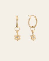 The Elsa Cherry Aquamarine Earrings from CAMELLIA feature gold vermeil hoops with dangling flower-shaped charms, each centered with an aquamarine gemstone, March's birthstone, all displayed on a light cream background.