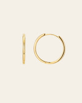 The 25mm Mother Hoops by CAMELLIA are showcased on a plain background, featuring one earring side view and the other front view. Crafted in 14K Yellow Gold Vermeil, they are hypoallergenic for sensitive ears and add a timeless touch to any ensemble.