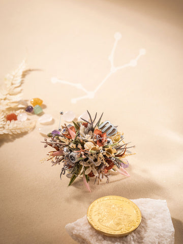 A small bouquet of dried preserved flowers and gemstones rests on a beige surface, alongside a gold coin and rock. Completing the scene is CAMELLIA's Virgo Flower Ring, a delicate handcrafted adjustable piece, set against a constellation pattern in the background. A small bouquet of dried preserved flowers and gemstones rests on a beige surface, alongside a gold coin and rock. Completing the scene is CAMELLIA's Virgo Flower Ring, a delicate handcrafted adjustable piece, set against a constellation pattern in the background.