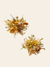 The Love In The Sunset Wind Wedding Flower Rings by CAMELLIA feature ornate floral brooches with gold accents and handcrafted details, showcasing an array of dried flowers and leaves on a light beige background.