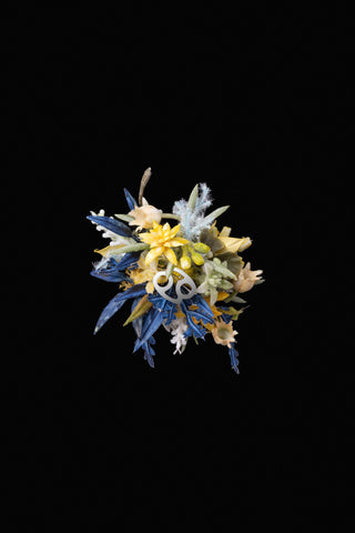 A handcrafted Cancer Flower Ring by CAMELLIA, made in New York, features a floral design with yellow and blue flowers and silver foliage on a black background with white geometric shapes reminiscent of a custom symbol. A handcrafted Cancer Flower Ring by CAMELLIA, made in New York, features a floral design with yellow and blue flowers and silver foliage on a black background with white geometric shapes reminiscent of a custom symbol.