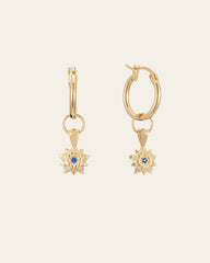 The Elsa Holly Tanzanite Earrings by CAMELLIA feature gold hoops with floral pendants and central blue gemstones, elegantly crafted in 14K Yellow Gold Vermeil for a timeless look on any occasion.