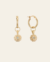 CAMELLIA's Elsa Marigold Tourmaline Earrings are gold hoops with dangling flower-shaped charms, each highlighting a small central blue tourmaline gemstone—October's birthstone—set against a plain background.