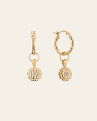 CAMELLIA's Elsa Marigold Tourmaline Earrings are gold hoops with dangling flower-shaped charms, each highlighting a small central blue tourmaline gemstone—October's birthstone—set against a plain background.