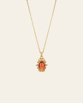 The Vivien Garnet Necklace by CAMELLIA showcases a garnet red oval stone pendant encircled with gemstones, designed to be hypoallergenic for comfort.
