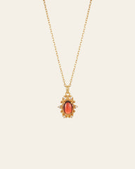 The Vivien Garnet Necklace by CAMELLIA showcases a garnet red oval stone pendant encircled with gemstones, designed to be hypoallergenic for comfort.